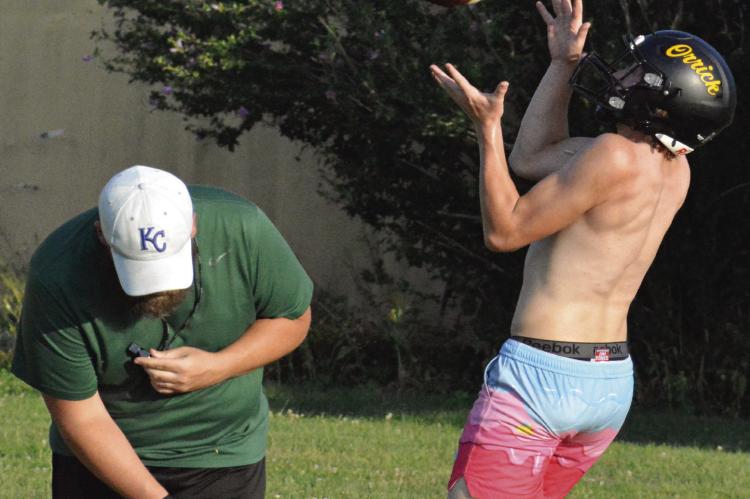 ORRICK ASSISTANT COACH Jake Waters (left) ducks as Gage Tebbe hauls in a deep ball during team camp for varsity 8-man football. SHAWN RONEY | Staff