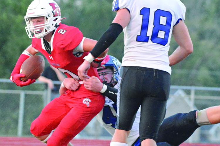 KEEPING THE FOOTBALL clutched with his right hand, Richmond’s Bryer Farnan fights through a tackle en route to a second-quarter catch-and-run touchdown during the Spartans’ Aug. 30 loss to visiting Harrisonville. SHAWN RONEY | Staff