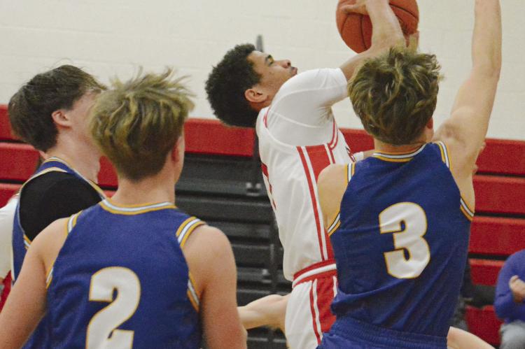 BRICE DOME (center) clutches onto the basketball as he drives into a nest of Hornets to attempt a contested layup during Richmond’s fifth-place game with Penney of Hamilton in the Lawson Invitational Tournament. SHAWN RONEY | Staff