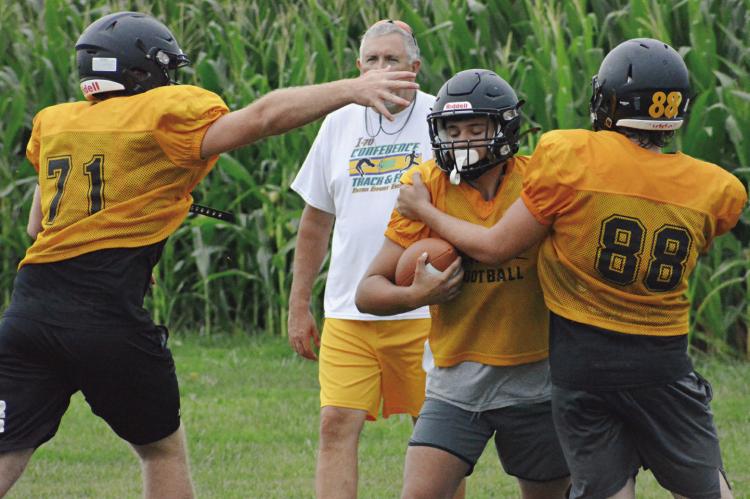 TUCKER GREER (No. 71) and Ashton Toland (No. 88) display their pass rushing skills during Orrick’s 8-man football team camp Monday on the program’s practice field. SHAWN RONEY | Staff