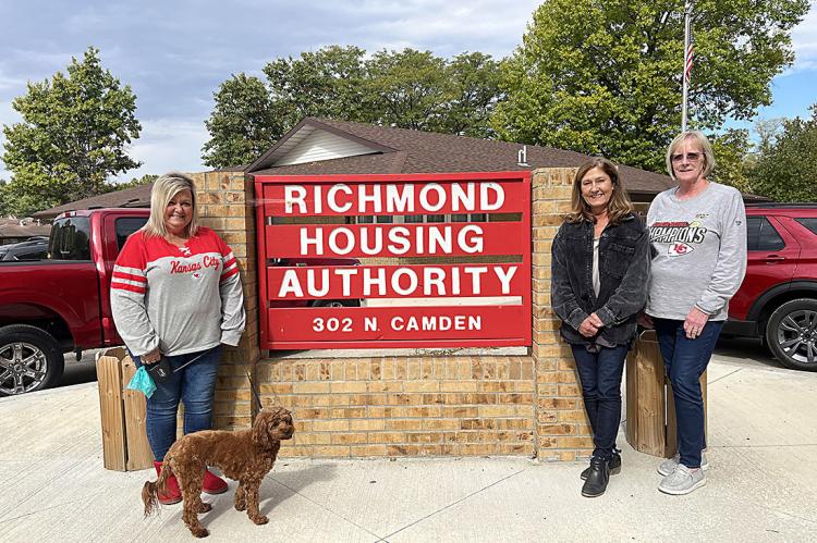 APRIL MAULSBY; Cali, the office pup; Valerie MacDonald; and Helen Sinderson are standing in front of a sign that the Housing Authority’s maintenance department homecrafted themselves. Maulsby says she and her team are impressed by the rating and effort that has been put into it. SOPHIA BALES | Staff