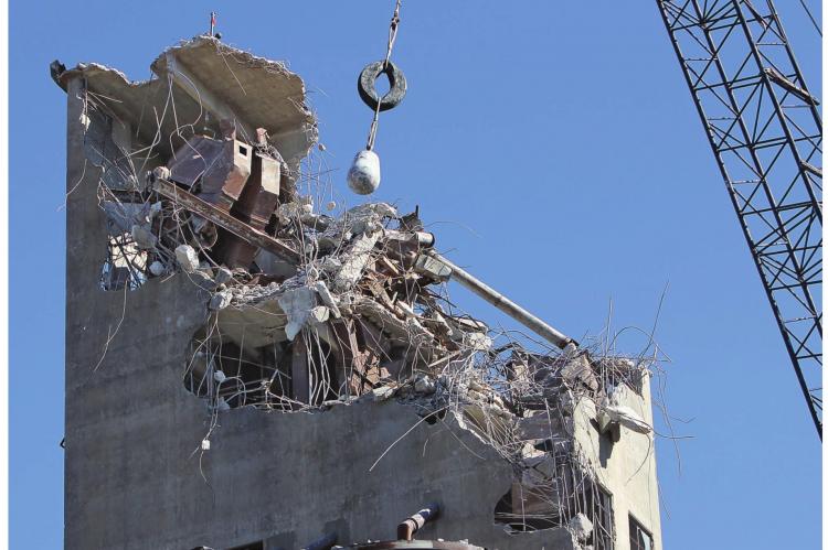UNDER A BLUE SKY, a wrecking ball swings back and forth, pounding the concrete body and sometimes dropping destructively into the organs of the old grain elevator in Richmond as part of the slow, careful process of demolition. Last week’s work is sure to extend into this week and beyond. J.C. VENTIMIGLIA | Staff