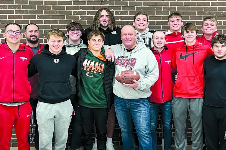 MIKE KARL IS HONORED to receive a football signed by the Richmond High football team seniors. Shown are, back row, from left, coach Nick Persell, Larry Penniston, Jack Gouge, Hunter Bowman, Thomas Murphy, Eli Steele and Joe Burch; front row, Joshua Pyle, Donivin Williams, Aidan Ivison, Bailon Stockton, Karl, Trevin Quick, Dayne Loftin, TJ Rush and Donte Pringle. SOPHIA BALES | Staff
