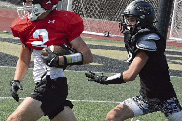 HOLDING THE FOOTBALL firmly with his left arm, Richmond wide receiver Bryer Farnan pulls away on a catch-andrun play recently during a scrimmage rep with Excelsior Springs at Tiger Stadium. SHAWN RONEY | Staff