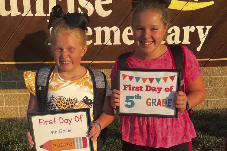 ANNA AND ABIGAIL GARLAND stand ready with their firstday- of-school signs Wednesday at Sunrise Elementary.