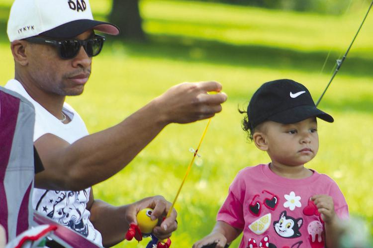 TEVIN ROBINSON helps his daughter, Maven, prepare her fishing line during the fishing competition. SHARON DONAT | Staff