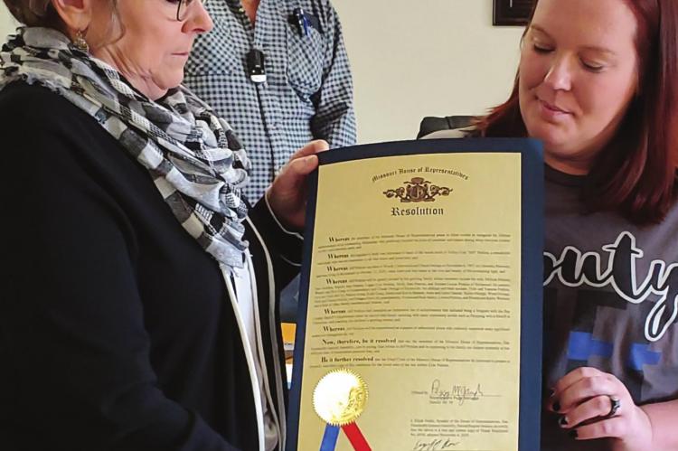 A SERVANT REMEMBERED: Missouri State Rep. Peggy McGaugh presents Melissa Perkins a House resolution. The document recognizes the service of Perkins’ husband, the late Jeffrey “Jeff” Cole Perkins, a Ray County Sheriff’s Office sergeant. From left, front, are McGaugh and Perkins. Behind them is Commissioner Jerry Bishop. JANIS KINCAID | Submission