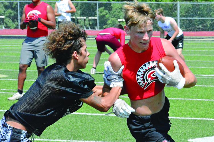 BRYER FARNAN shields the ball with his left arm as he’s “tackled” with a two-hand touch after a short catch-and-run play for the Spartans during Tuesday’s 7-on-7 scrimmage with Excelsior Springs at Tiger Stadium. SHAWN RONEY | Staff