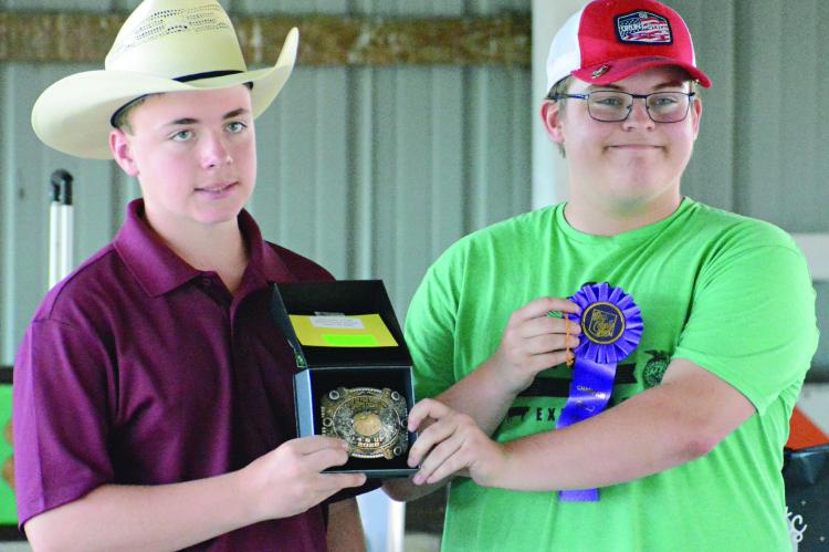 WESTON COVEY (left) helps display hardware won by Hunter Crowley in shooting sports during this year’s Ray County Fair in Richmond. SHAWN RONEY | Staff