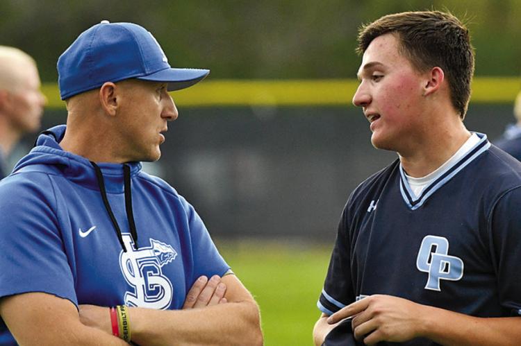 CALE LYONS (left) confers with a player during a previous baseball practice. Lyons balances coaching and teaching with ongoing service in the Missouri Army National Guard. Submitted
