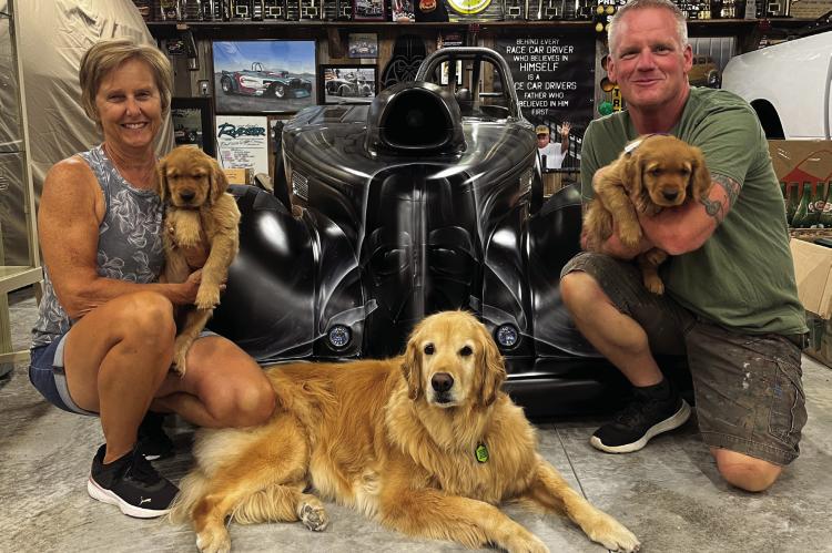 BUSINESS OWNERS Vicki and Paul Comeau with their golden retrievers, Quinn, Clementine and Rocket, sit in front of a Darth Vader-themed race car. The Comeaus are excited to live in Richmond. SOPHIA BALES | Staff