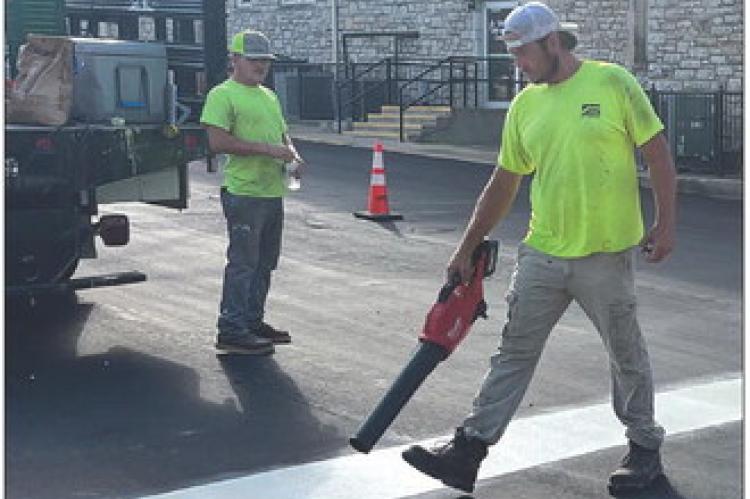 K AND G STRIPING LLC staffers Tyler Geesaman (left) and Bobby Crossley work on N.W. Main Street Wednesday morning. SOPHIA BALES | Staff