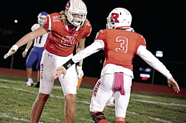 RICHMOND QUARTERBACK Donivin Williams, No. 3, gives a low five to lineman and fellow senior Jack Gogue after Williams’ last-second TD pass to Eli Steele puts the Spartans ahead of Holden 24-20 Oct. 7 at Spartan Stadium. A two-point conversion run by Aidan Ivison then provides the final points of Richmond’s Missouri River Valley Conference East Division victory. SHAWN RONEY | Staff