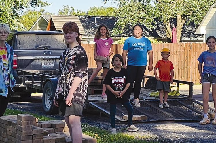 Members build patio with brick pavers around a fire pit. Submitted