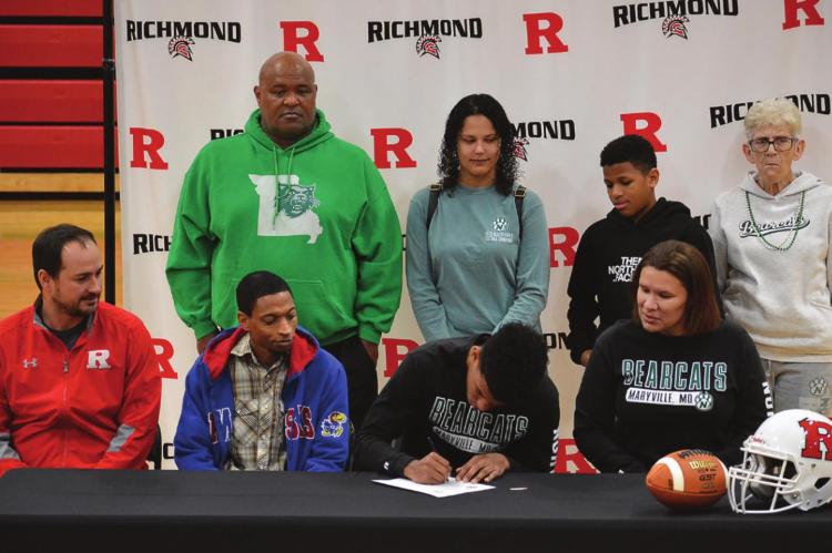 SURROUNDED by his coach and others close to him, Richmond senior Jordan Alexander signs his letter of intent to play football at NWMSU. SHAWN RONEY | Staff