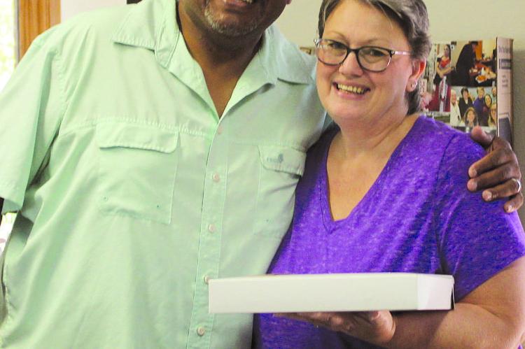 DEON FIELDS (left) brings Felicia Farabee fresh-baked cookies on her last day at Central Missouri Community Credit Union after 20 years of service. SHARON DONAT | Staff