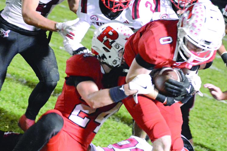RYAN SHARP (left) hangs onto Richmond teammate Nolan Quick as a swarm of Hornets converge on them following Chillicothe’s fourth-quarter onside kick attempt in district 11-man football action. SHAWN RONEY | Staff
