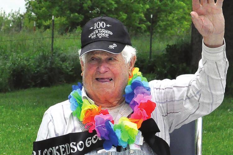 SURPRISED by dozens of drive-by birthday well-wishers, Ted Thomas, 100, gives them a wave. SHAWN RONEY | Staff