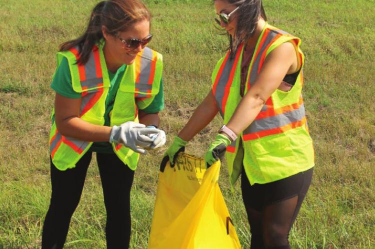 VANESSA CLARK lifts debris from Highway 13. Her sister, Alisha Brandham, holds open the bag. J.C. VENTIMIGLIA | Staff