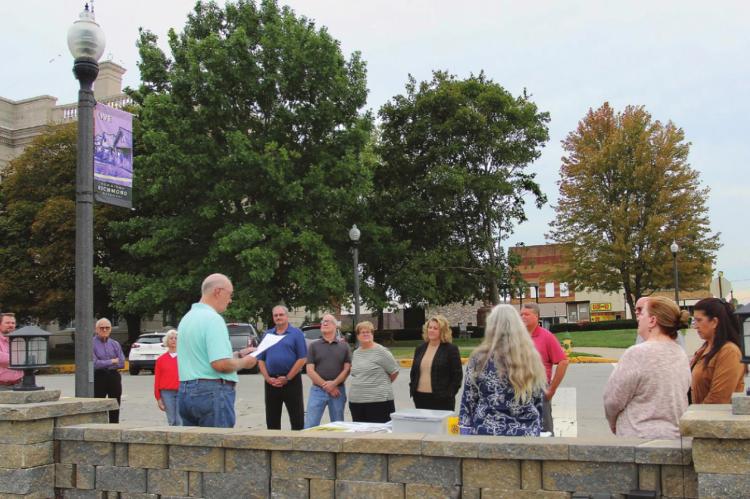 STANDING ACROSS from the Ray County Courthouse in front of the city park being built at West North Main and North College streets, Ray County Bicentennial Committee member Dr. Hal Middleton reads from a paper telling the community leaders standing in front of him on the sidewalk what will go into the time capsule. J.C. VENTIMIGLIA | Staff
