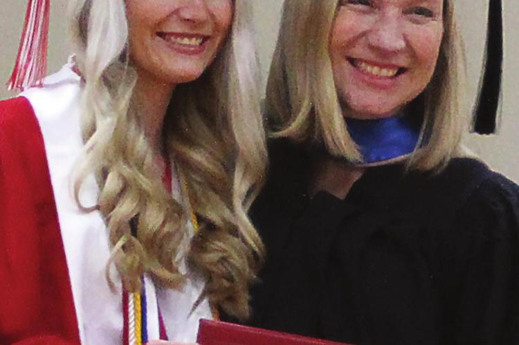 GRADUATION is not typical due to the school year and graduation date changes forced on Missouri school districts by the novel coronavirus, COVID-19. Dice Photography photographer David Dice says the virus cut his business by about 95%. During a mock graduation ceremony, Richmond High School valedictorian Abby Vandiver receives her diploma from her mother, Richmond Board of Education President Penny Vandiver. Both look toward Dice to capture the moment. J.C. VENTIMIGLIA | Staff