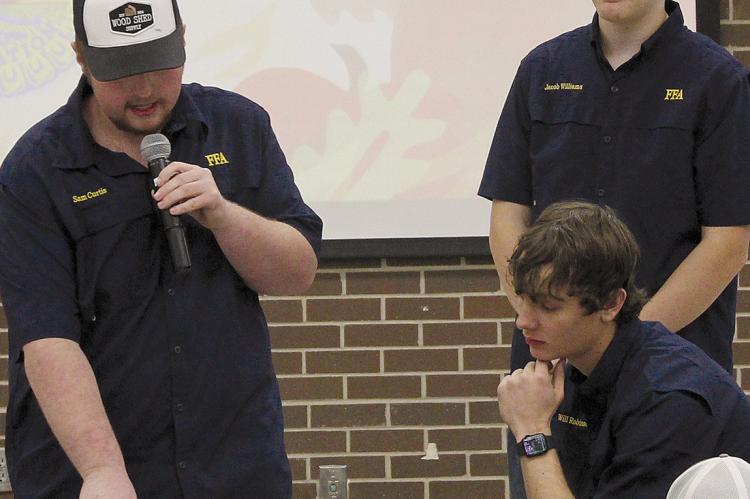 SAM CURTIS (from left), Will Robinson and Jacob Williams announce the winners of the silent auction to the over 90 attendees of the FFA Fall Harvest Dinner. SHARON DONAT | Staff
