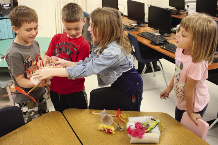 COOPER BURNETT (from left), Chance Wegley, Averionna Lee and Barbara Floyd retrieve their group zip line device to test in Vest’s class. They are seating a doll in place to test the quality of their zip line — that is, whether it will hold her. In this case, the group’s device did indeed work.