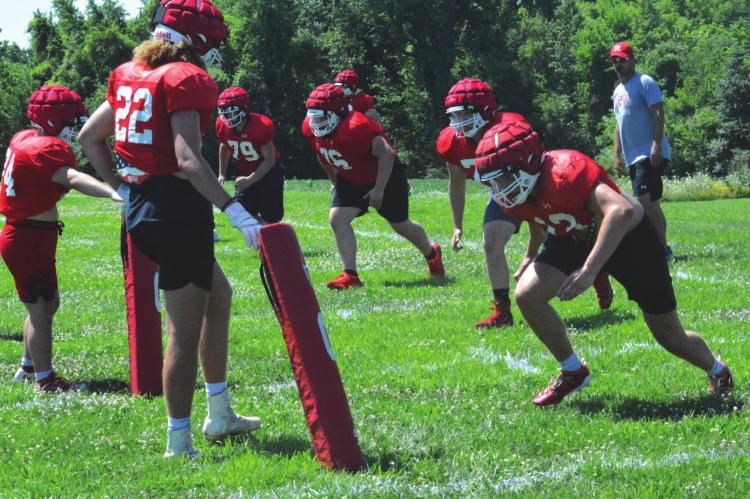 SPORTING HIS shades and ballcap, Richmond varsity football coach Nick Persell watches a group of his Spartans practice the rolling tackle drill Monday on the Richmond practice field. SHAWN RONEY | Staff
