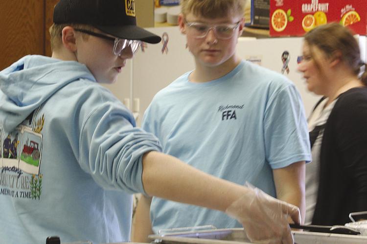 HUNTER HOLLOWAY (from left) serves food alongside Isaac Kaylor as Sarah Brown helps coordinate meal preparation during a student-led community event. MIRANDA JAMISON | Staff