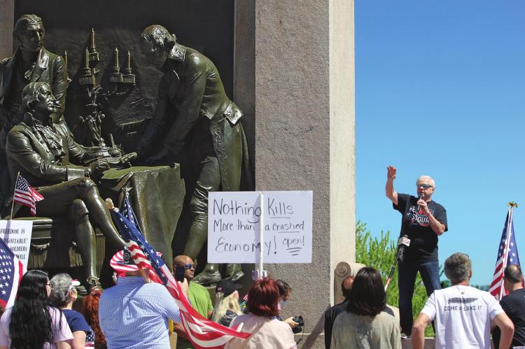 RADIO SHOW HOST Dave “Super Dave” Day warms up the Reopen Missouri crowd of about 500 people at the “Signing of the Treaty” sculpture on the Capitol grounds Tuesday in Jefferson City. Several crowd members carry signs that denounce Gov. Mike Parson for issuing a stay-home order.