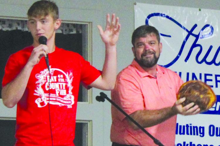 JUSTIN WRISINGER (right) hands Xavior Gaskins of Orrick FFA the mic to auction off his ham. SHARON DONAT | Staff