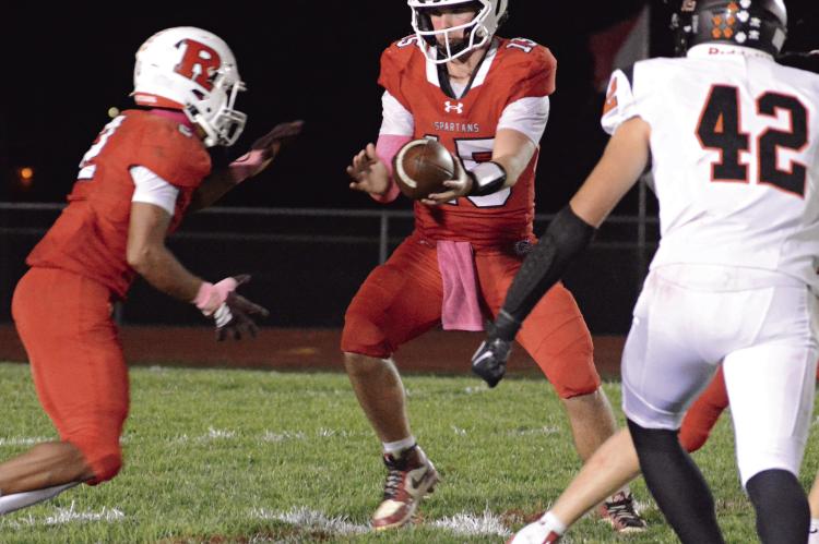 SHORTLY AFTER Richmond’s goal line stand, running back Cyrus Jackson (left) prepares for a handoff from quarterback Jacob Lieberknecht to help the Spartans run out the clock and end Knob Noster’s bid for a perfect season. SHAWN RONEY | Staff