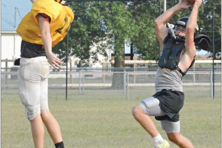 JEFF ROHDE (right), who normally plays quarterback on offense, gets in some time at receiver and nabs a pass while covered by Orrick teammate Logan Dennis Tuesday on the school’s practice field. SHAWN RONEY | Staff