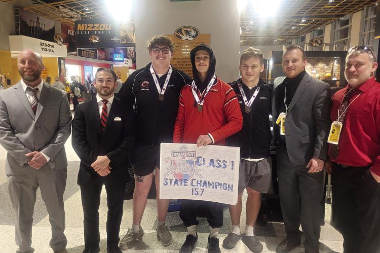 RICHMOND JUNIOR Elijah Sanders displays his championshp poster after winning the 157-pound title at the Class 1 state boys wrestling tournament, held Feb. 22-23 at Mizzou Arena in Columbia. Also pictured are, from left, Nic Joint; Kayhan Karimi; senior Larry Penniston, sixth place, 285; senior Aidan Ivison, fifth place, 190; Cody Hogan, Richmond coach; and Aaron Misenhelter. JORDAN HEBER | Submitted