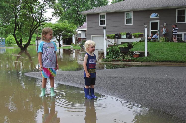 WITH WEST FORK of Crooked River overflowing, 6-year-old Ryann Madget and Reis Madget, 2, wear boots June 25 while standing in the water on Brookwood Street.