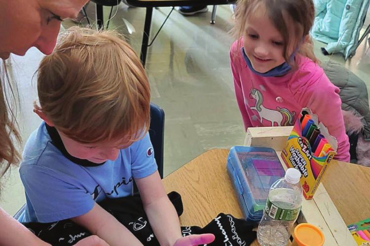 A BLACK LIGHT used by Chandra Carey reveals whether Meyer Hambrick and Ameila Ahart caught any germs from engaging in the paper activity.