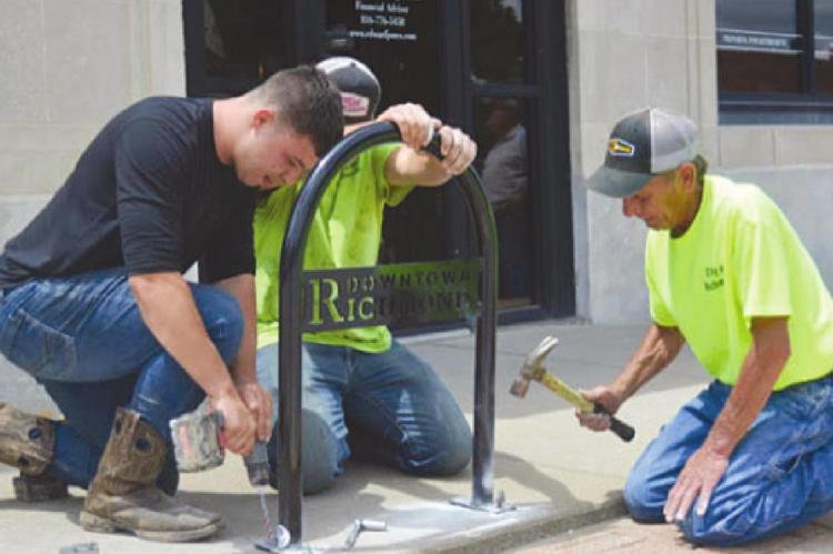 INSTALLING BIKE RACKS around Richmond’s downtown square are James Schwartz, Sean McCarter and Mike Outersky. Matching park benches are next. TARA ALTIS | Staff