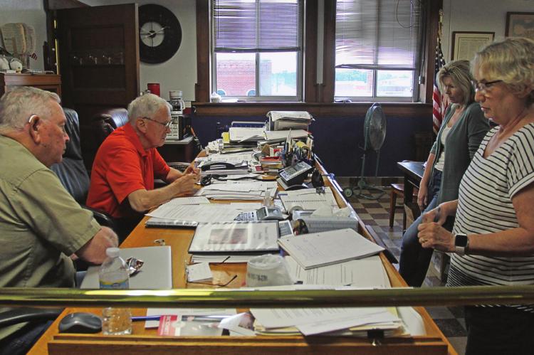 COMMISSIONERS listen to advice from state and national officials. From left are Commissioners Jerry Bishop and Bob King, Treasurer Melissa Holloway and County Clerk Glenda Powell.