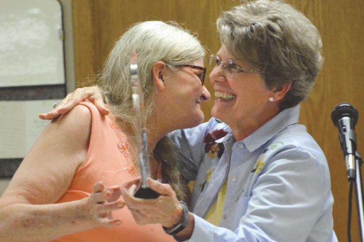 SISTERS Karen Grantham, left, and Linda Dawson embrace late in the ceremony honoring Charley, Eugene and Garold Skiles. The men will be remembered on the first Sunday in June and with a bridge in their name. SHAWN RONEY | Staff