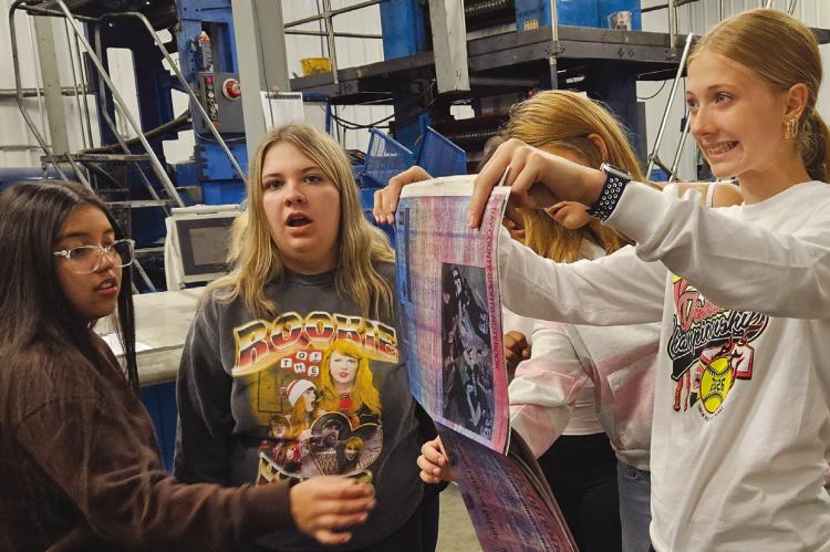 LEXINGTON HIGH SCHOOL journalism students inspect one of the first newspapers off the press, observing how the colors appear before adjustments are made. MIRANDA JAMISON | Staff