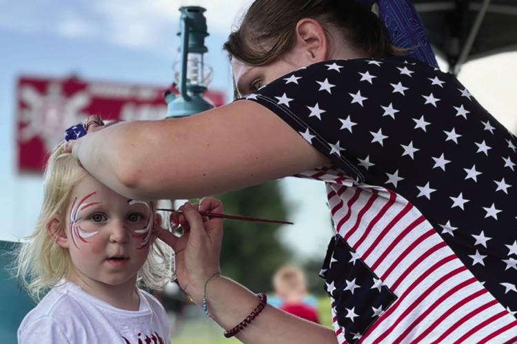 SAGE NIEMEIER sits still for her face painting of red, white and blue fireworks. JOSHUA BRUNGARDT | Staff