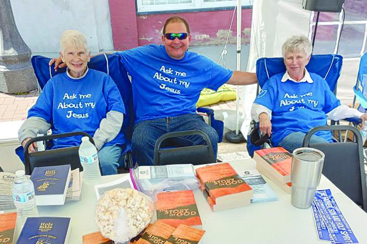 MARTHA GRUBBS (left), Drew Crowley and Zina Bush take their turn while volunteering for the Brothers and Sisters in Christ booth. Volunteers came from several congregations. DAVID DONALDSON | Staff