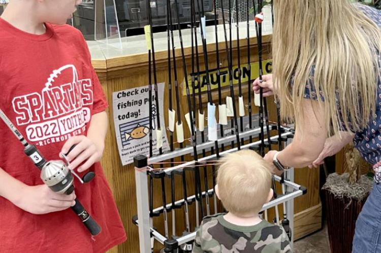 ISAAC, 10; Sam, 2; and Susan Duffett are sizing up the library’s newest item: fishing poles. SOPHIA BALES | Staff