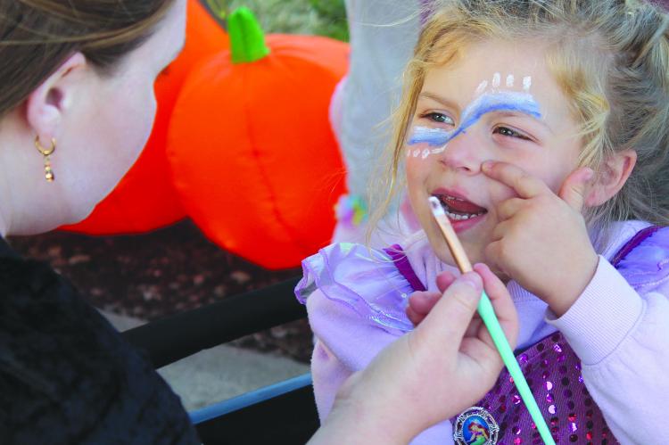 EMMERSON ATKISON directs the placement of her next face painting dot during the Hardin Fall Fest. SHARON DONAT | Staff