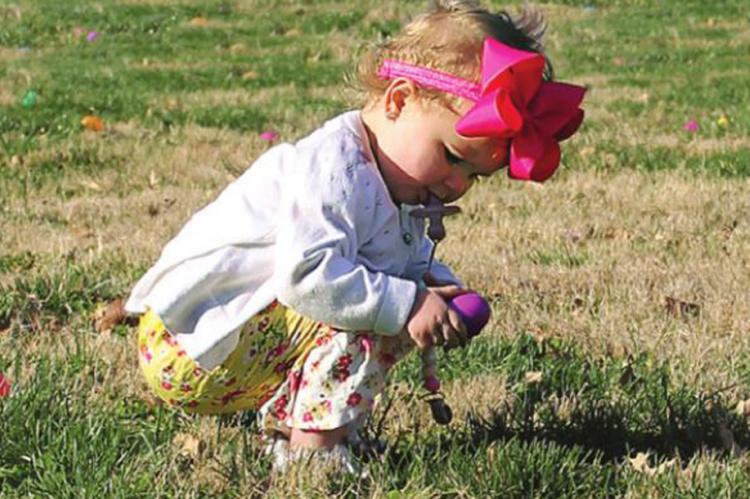 AT RICHMOND Parks and Recreation Department’s Community Easter Egg Hunt April 2 at Maurice Roberts Park, Kenlee Gilkey, 16 months, finds an egg. All hunters take the field under the protective eyes of Ray County Sheriff’s Office employees. In this case, Sgt. James Lawrence is near. J.C. VENTIMIGLIA | Staff
