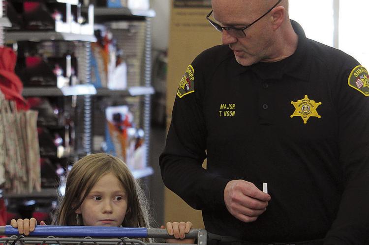 RAY COUNTY SHERIFF’S OFFICE Major Tom Noon (right) follows Kimber White to the toy aisle during the Shop with a Sheriff event. MIRANDA JAMISON | Staff