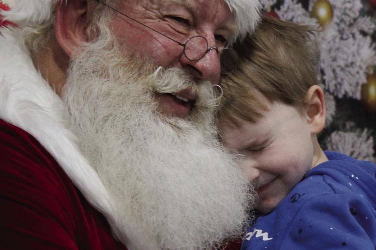 LANDON HARVIE wraps his arms around Santa, sharing a warm hug that shines with the magic of the holiday season. SHARON DONAT | Staff