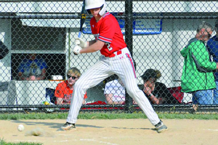 SOPHOMORE BRYER FARNAN takes a pitch low Tuesday at Fairground Park in Higginsville. SHAWN RONEY | Staff