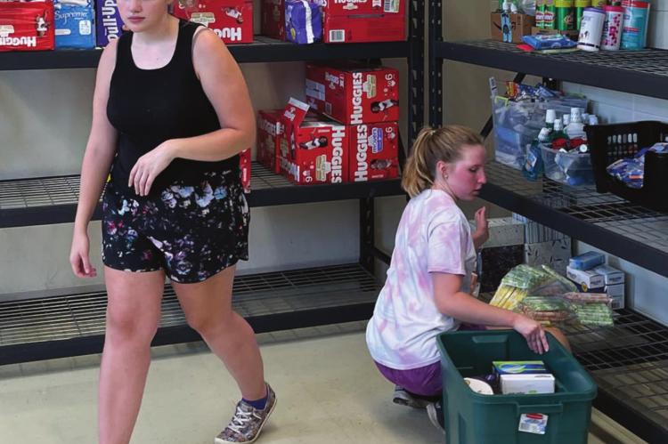 VOLUNTEERS: From left, Lily Wirsig and Allie Renfro work to stock the shelves at the Richmond United Methodist Church with GAP items for the new distribution facility at the church. Not pictured are volunteers Zane Renfro and Stephen Slater. Cathy Myers | Submitted