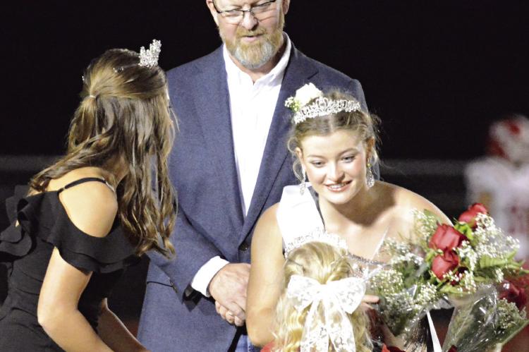 GRACE BOZARTH (from left), Richmond’s 2023 homecoming queen, and Bill Dooley watch as Isabelle Dooley receives flowers after being crowned the 2024 Richmond High School Homecoming Queen recently. SHAWN RONEY | Staff